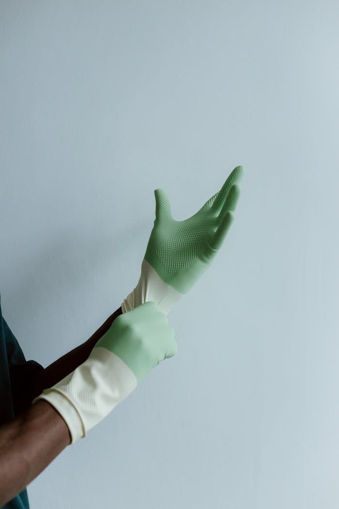A person wearing green latex gloves, ready for cleaning tasks, with space for text.